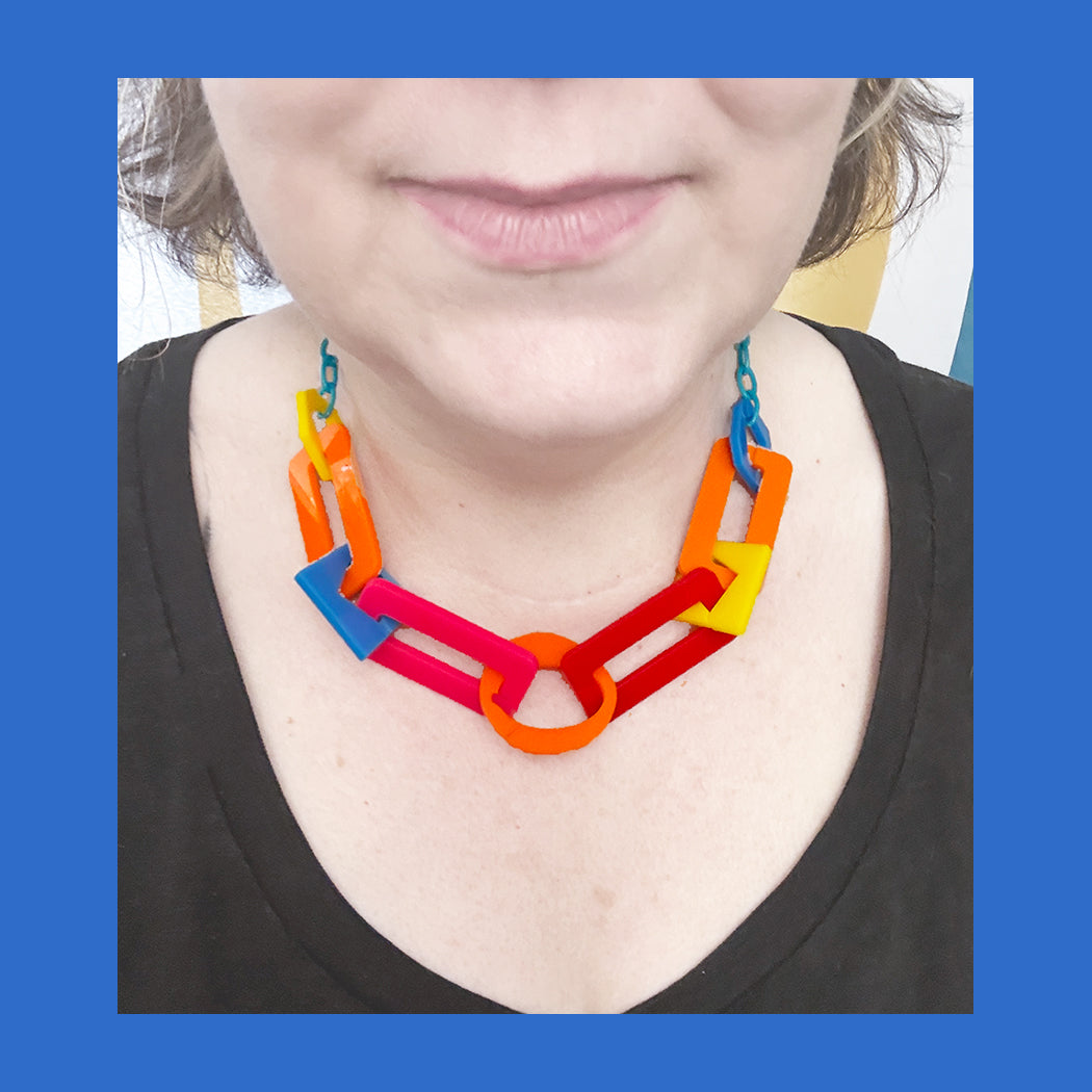 Person wearing a colorful chunky acrylic link necklace with a blue background.
