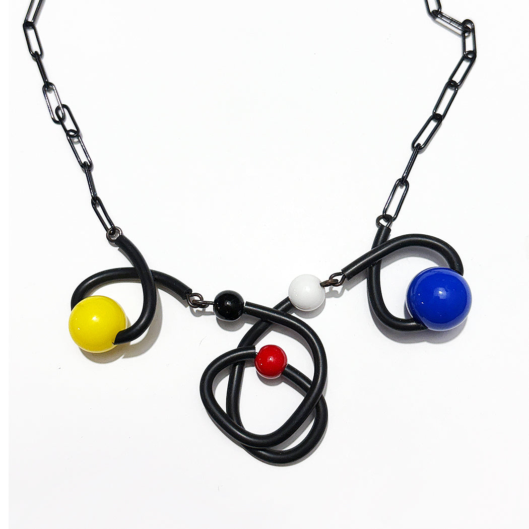 Miro art inspired Bounce necklace in black with yellow, black, red, and white multisized beads on black enamel chain from Audacious Studio.