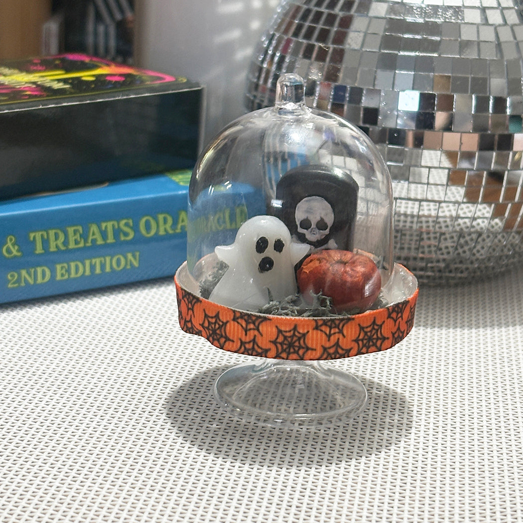 Halloween-themed display with pet ghost, headstone with skull and rustic pumpkin.