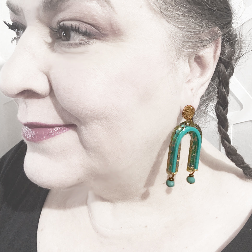 Model wearing geometric gold glitter arch earrings from Audacious Studio.