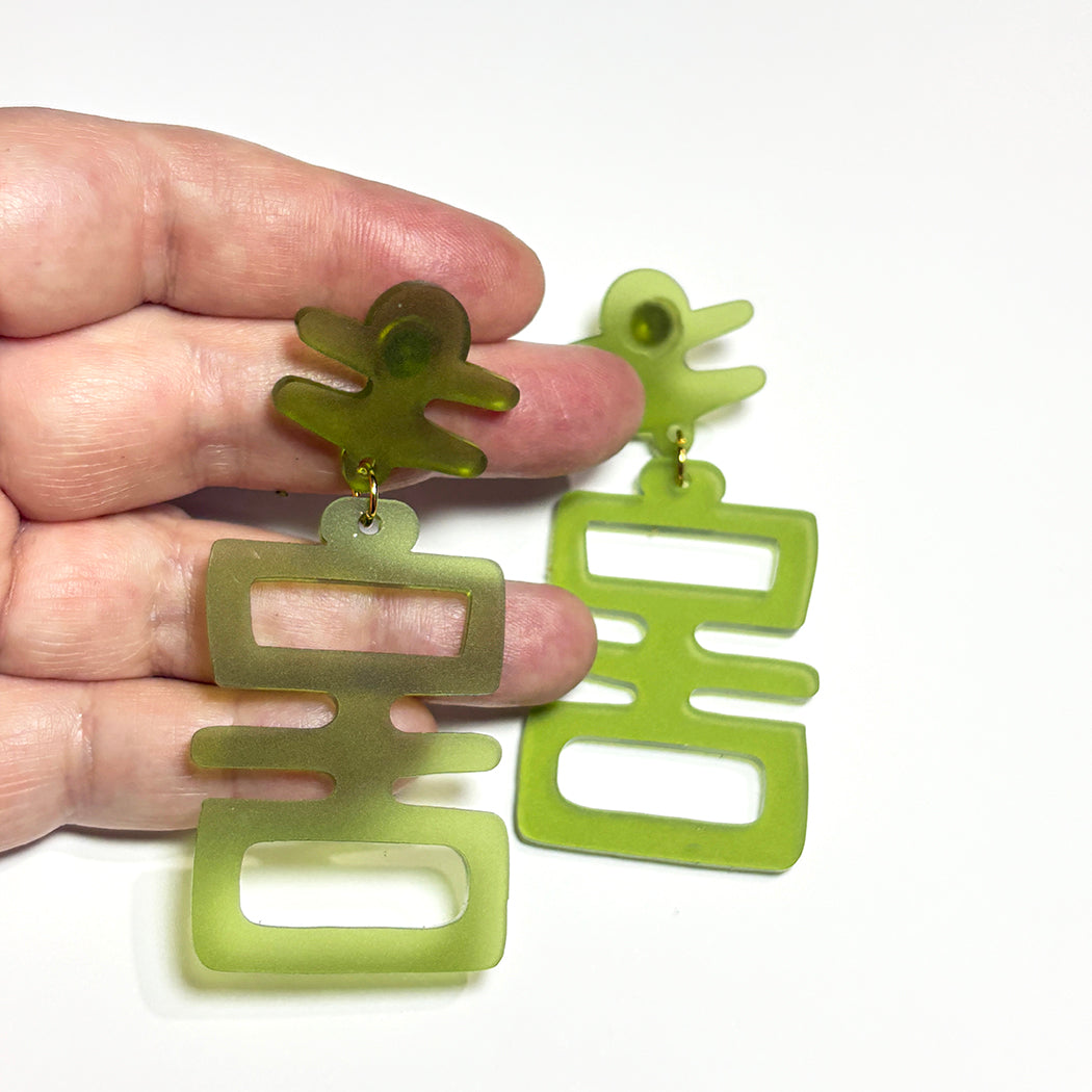 Hand holding Jade Idol statement earrings.