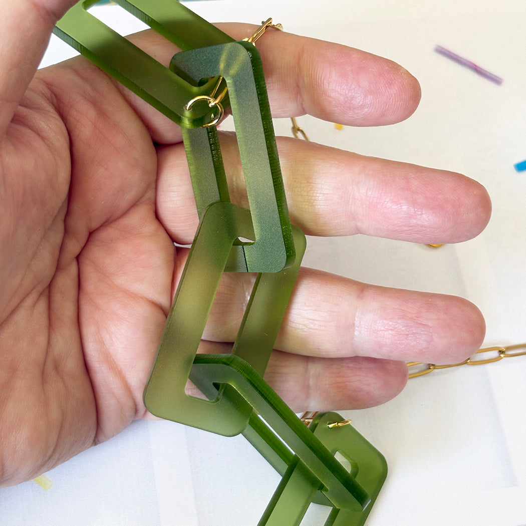Green plastic tool held by a hand on a white background