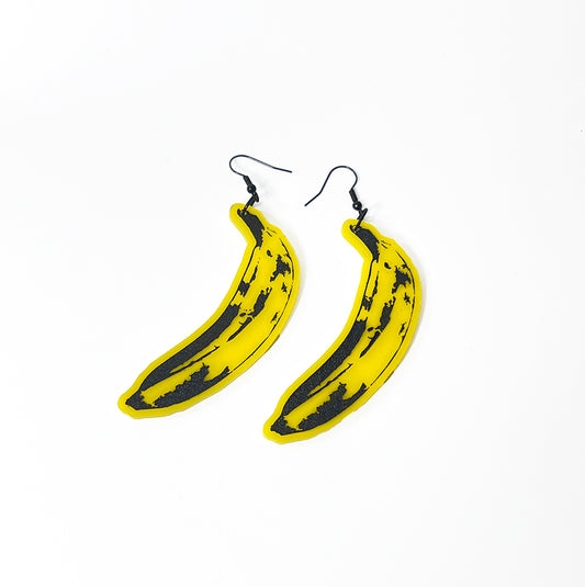 Yellow acrylic pop art banana earrings on white background