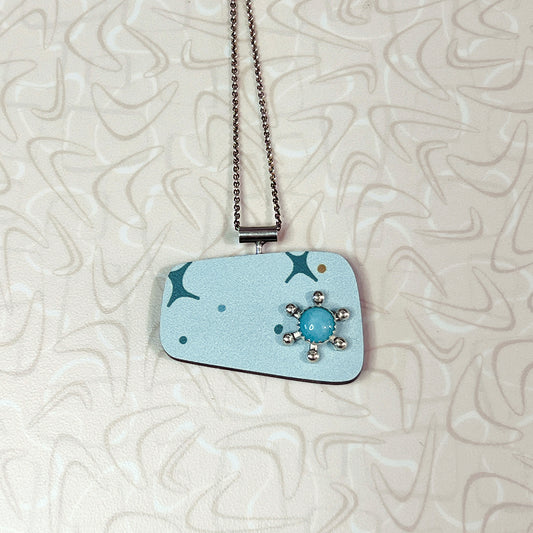 A blue starburst-shaped pendant with a central amazonite stone, set in a sterling silver chain.