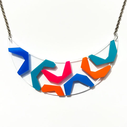 New Wave Style She Bop acrylic bib necklace with blue, teal, orange and hot pink acrylic on a clear background.