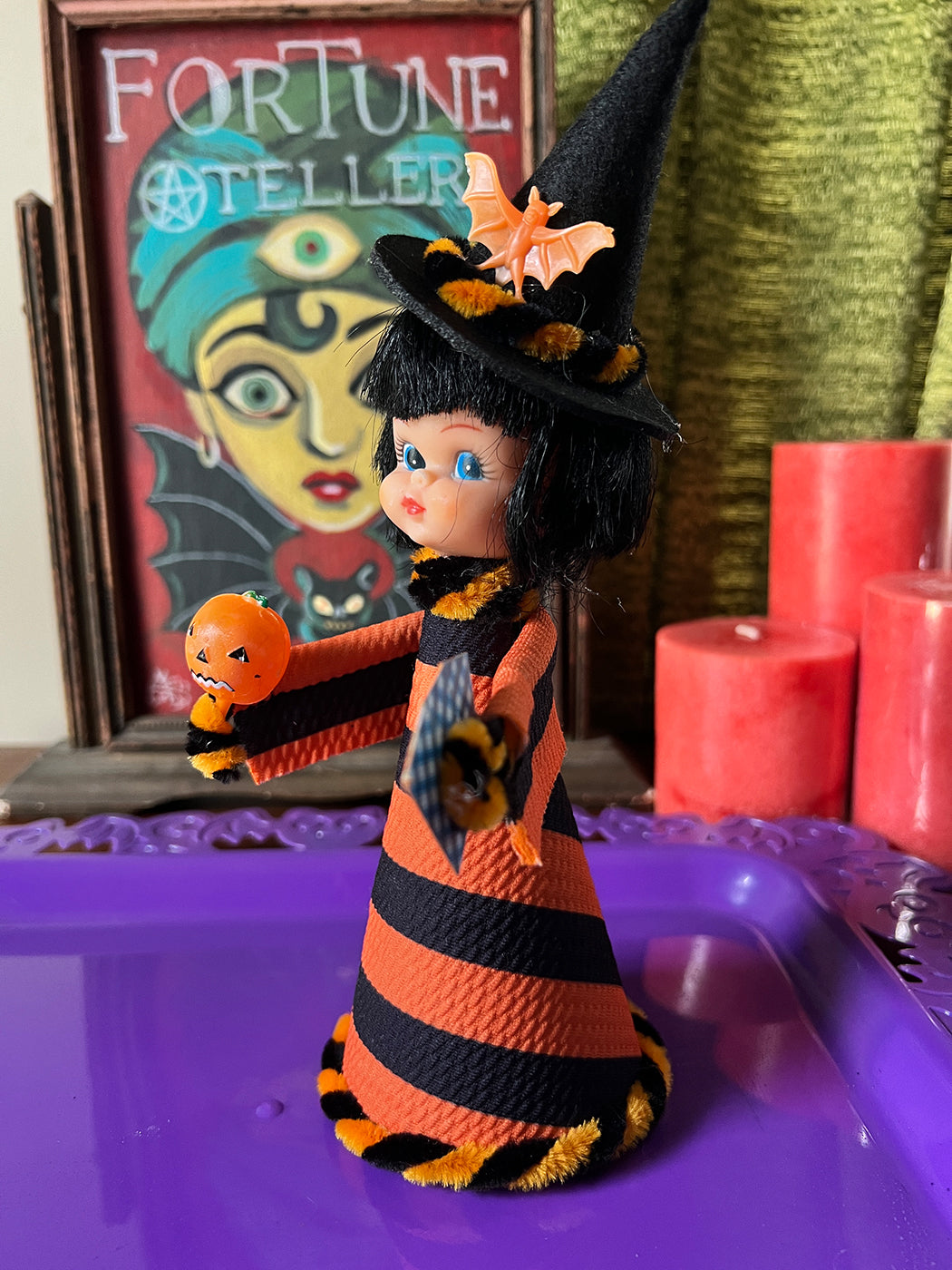 Halloween Witch doll with black and orange striped dress, surrounded by candles and a fortune teller cards.