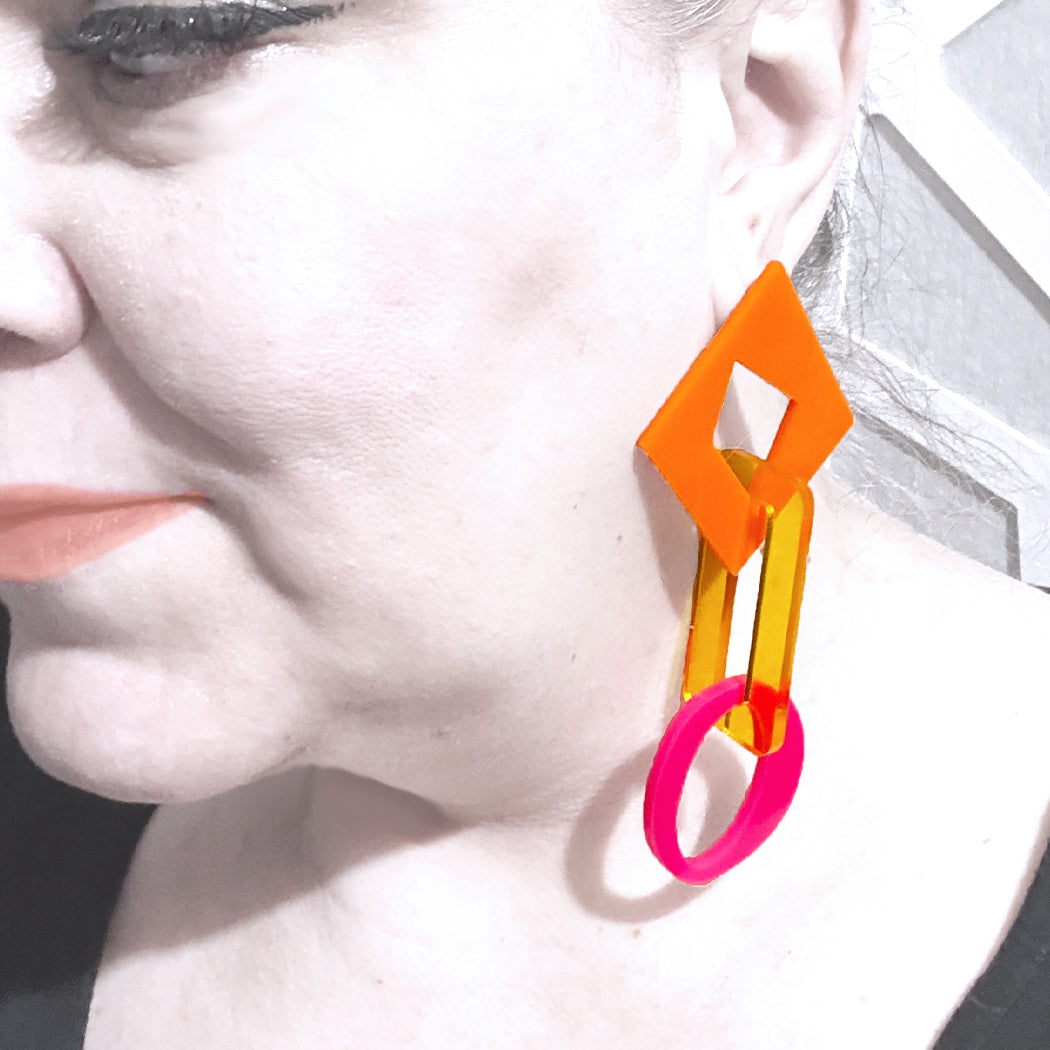 Model wearing large geometric acrylic chain link earrings from Audacious Studio.