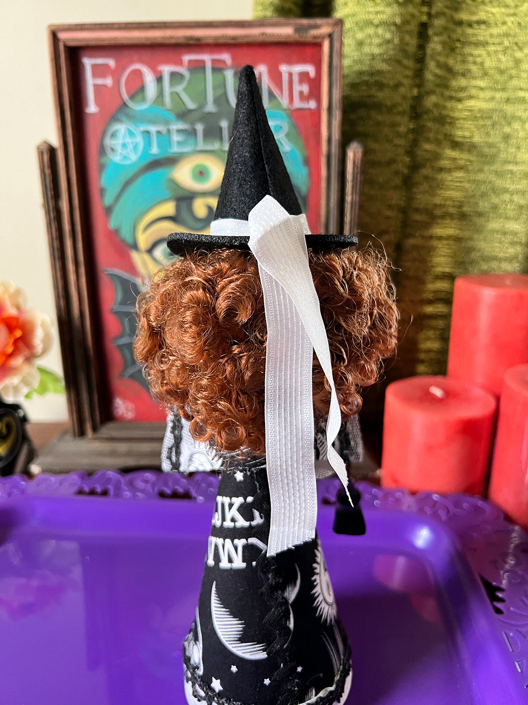 Halloween-themed decoration with a witch figurine, candles, and a fortune teller sign.