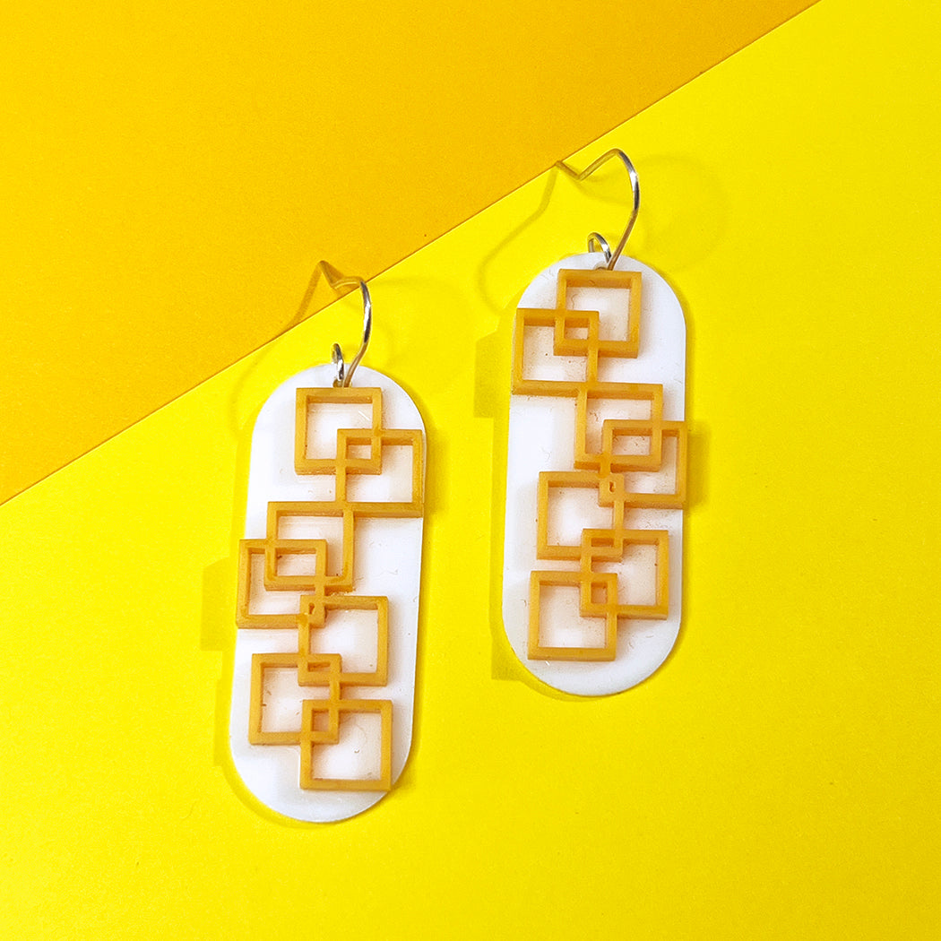 Closeup of tangerine square grid earrings in orange and white from by Barbe Jewelry.