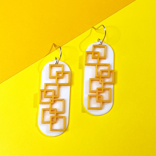 Closeup of tangerine square grid earrings in orange and white from by Barbe Jewelry.
