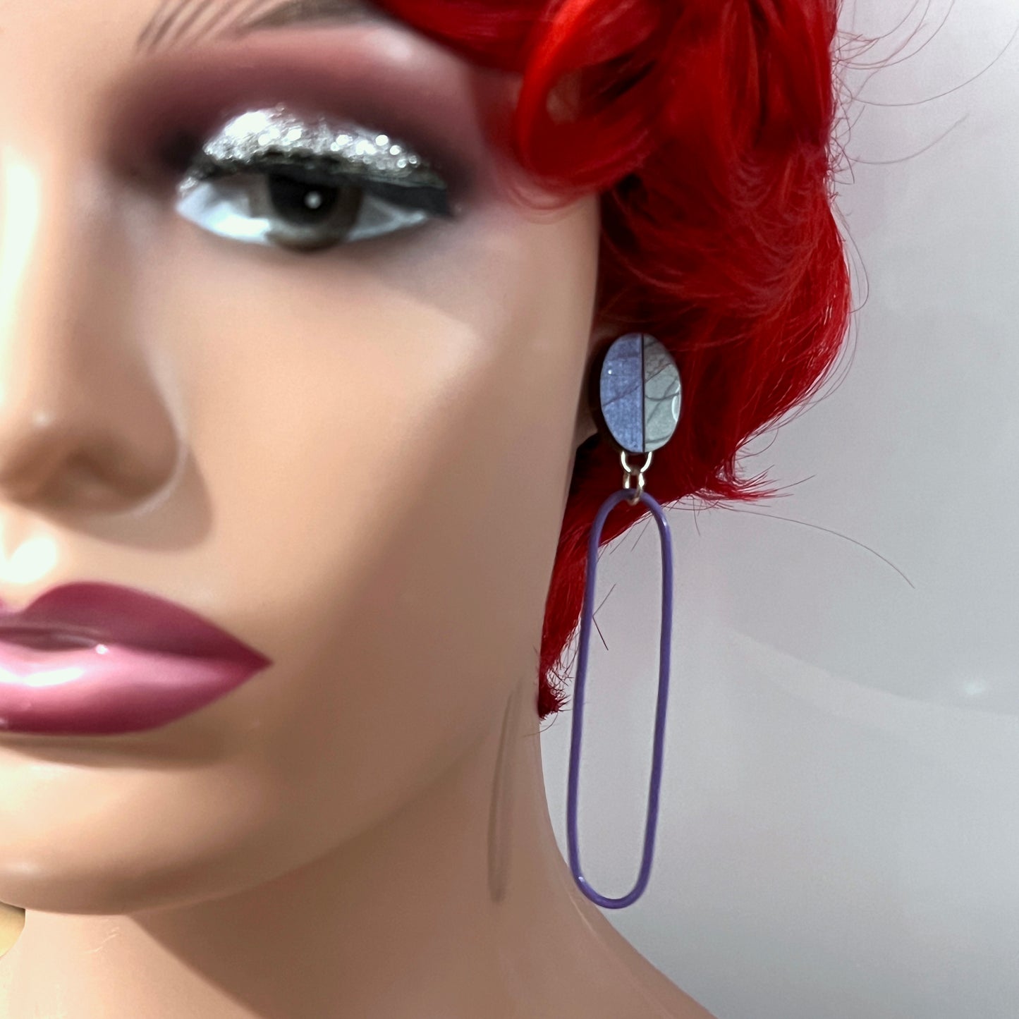 Long purple and gray recycled laminate, walnut and powercoated earring on mannequin head.