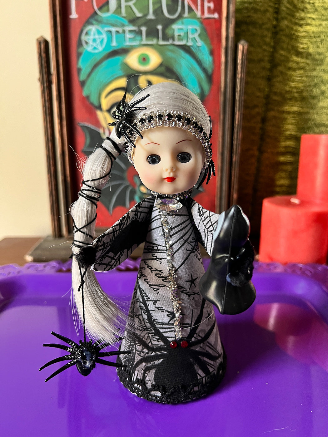 Vintage-style doll with intricate clothing and accessories on a purple surface, with a 'Fortune Teller' sign in the background.