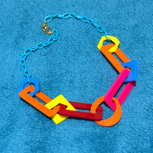 Colorful necklace with geometric links on a blue textured background