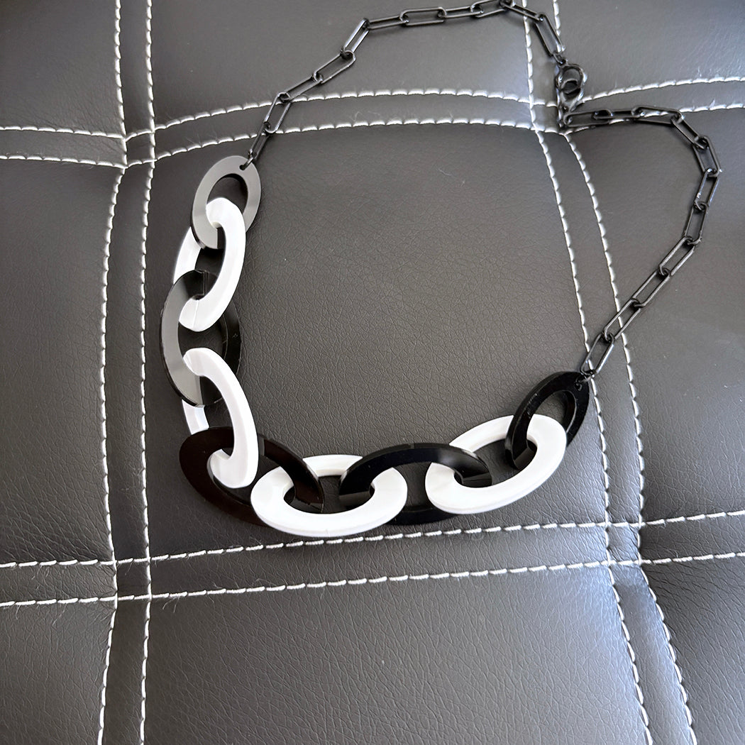 Black and white chain necklace on a textured gray surface