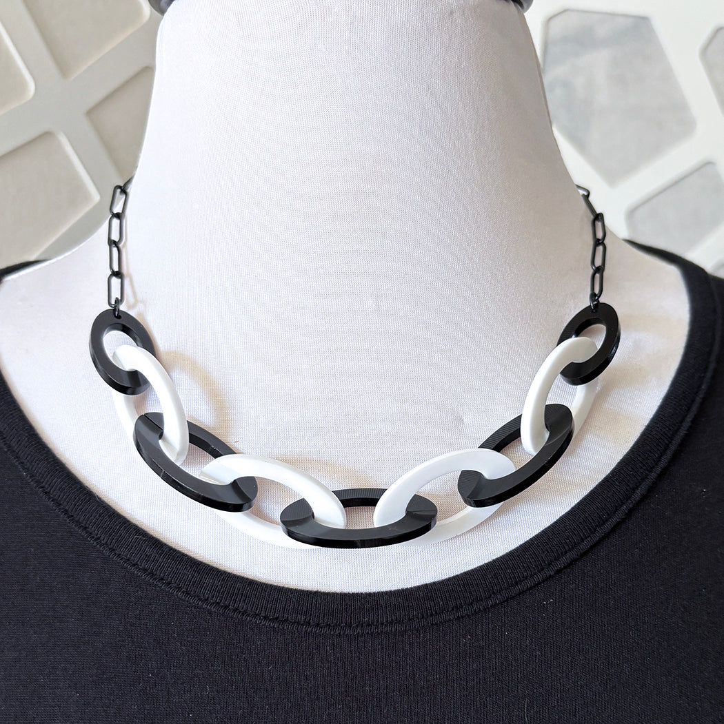 Black and white chain necklace on a mannequin bust against a neutral background