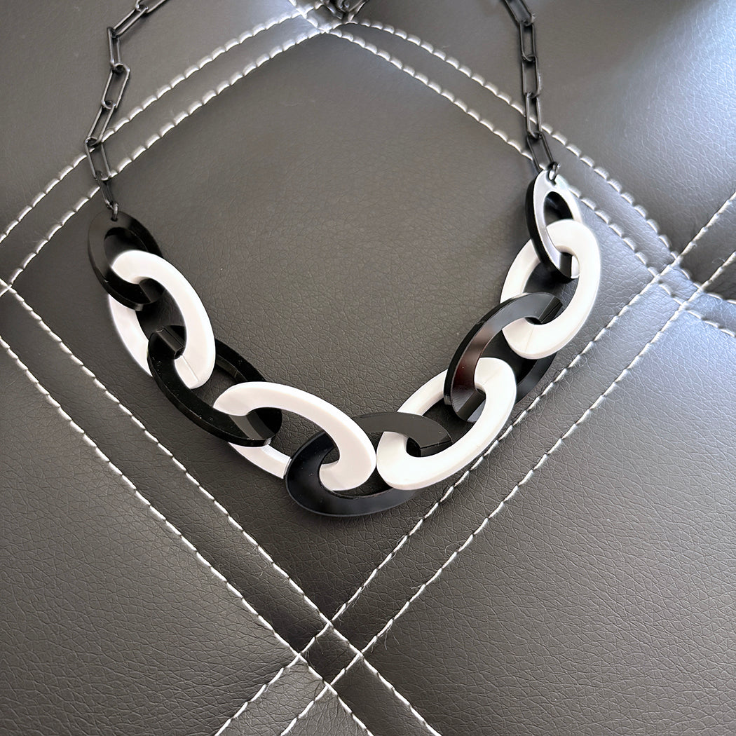 Black and white chain necklace on a textured gray surface
