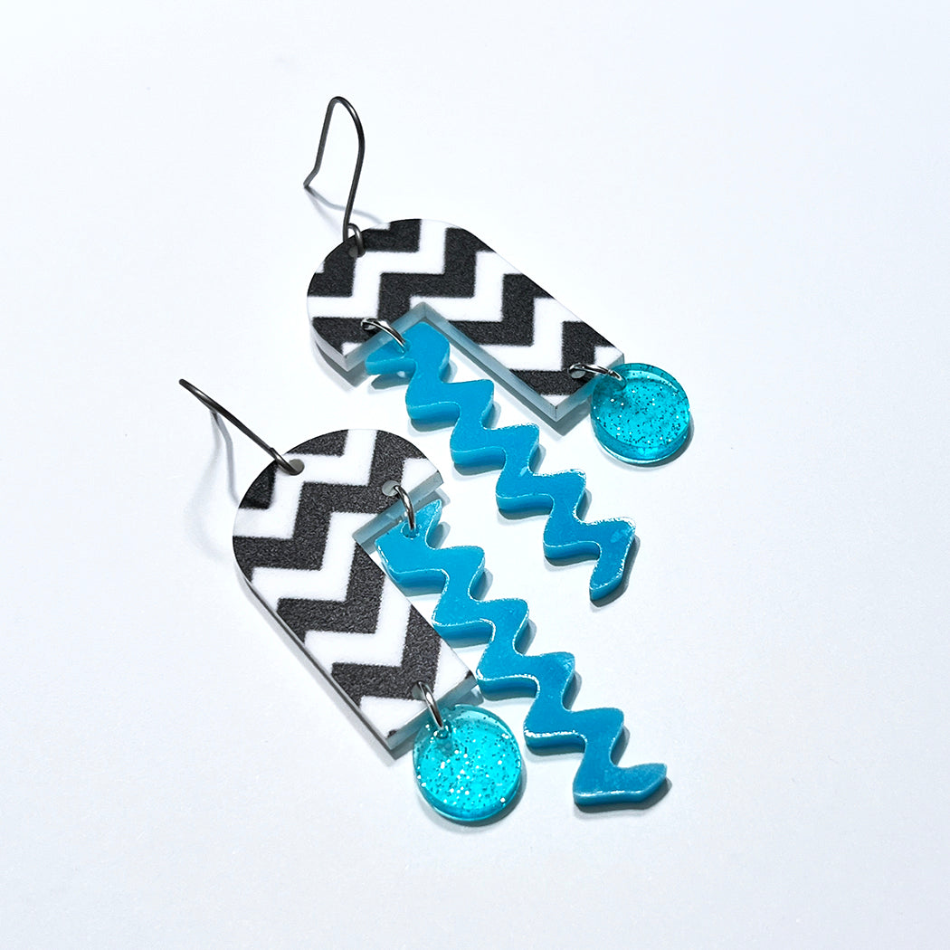 Close up of Arch mobile earrings on white background.
