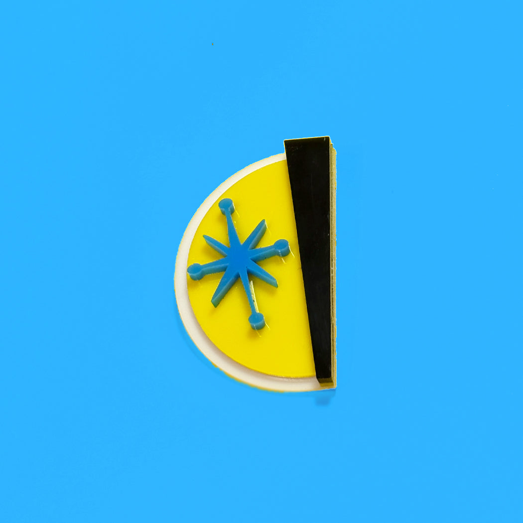 A modern, minimalist geometric pin featuring a yellow semicircle, a vertical black bar, a white curved accent, and a blue starburst in the center, set against a solid bright blue background.