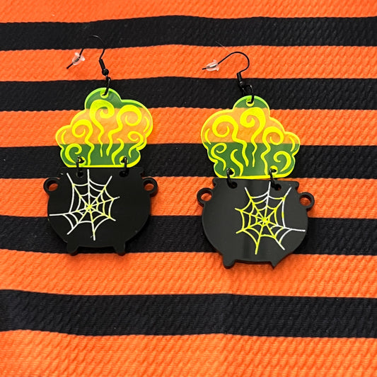 Halloween-themed earrings with cauldron and spider web design on an orange and black striped background.