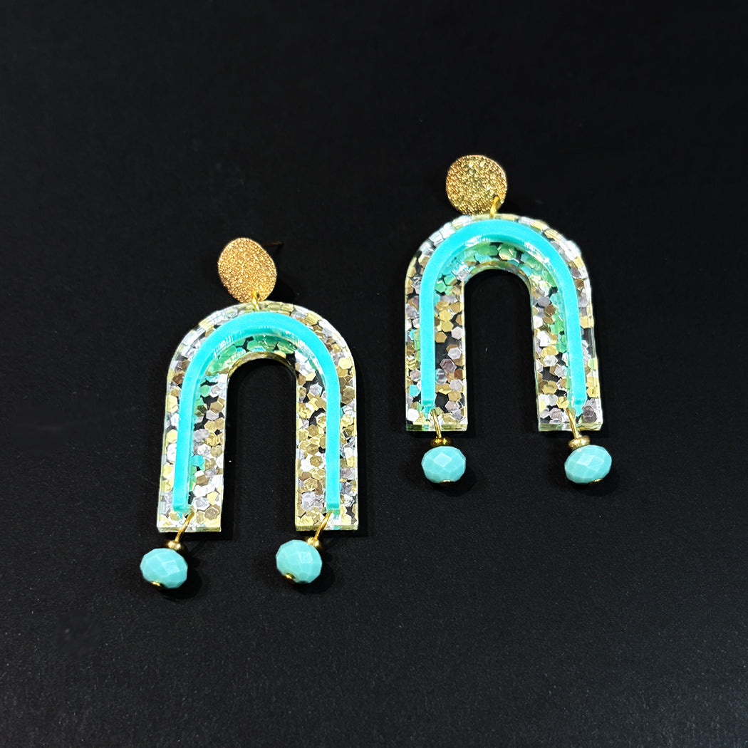 Close up of Golden Girl Glitter Acrylic arch earrings with glass bead dangles.