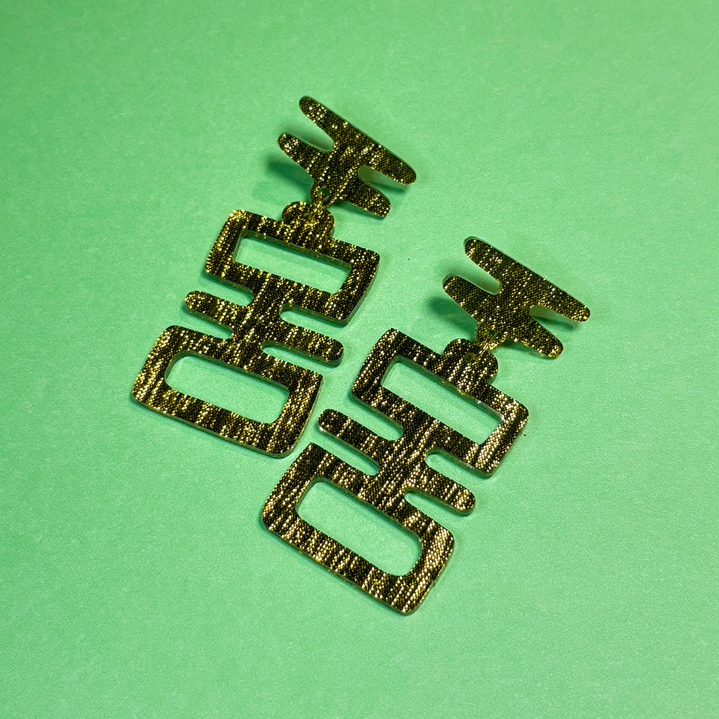 Close up of black and gold Golden Idol statement earrings from Audacious Studio. 