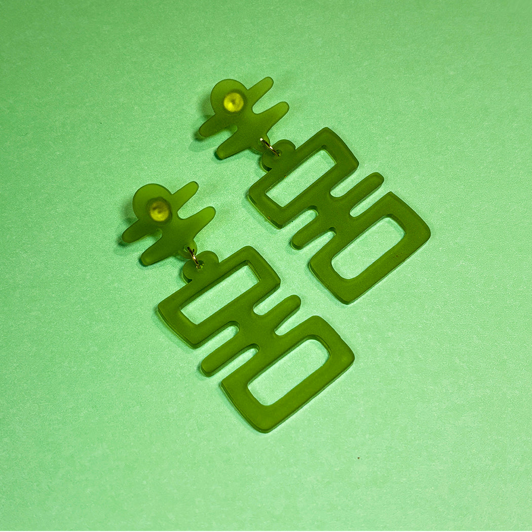 Close up of Jade Idol earrings on a green mesh background from Audacios Studio.