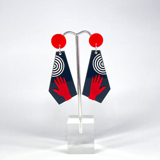 Photo of black trapezoid earrings with red hands and white stripes hanging from red dot posts.