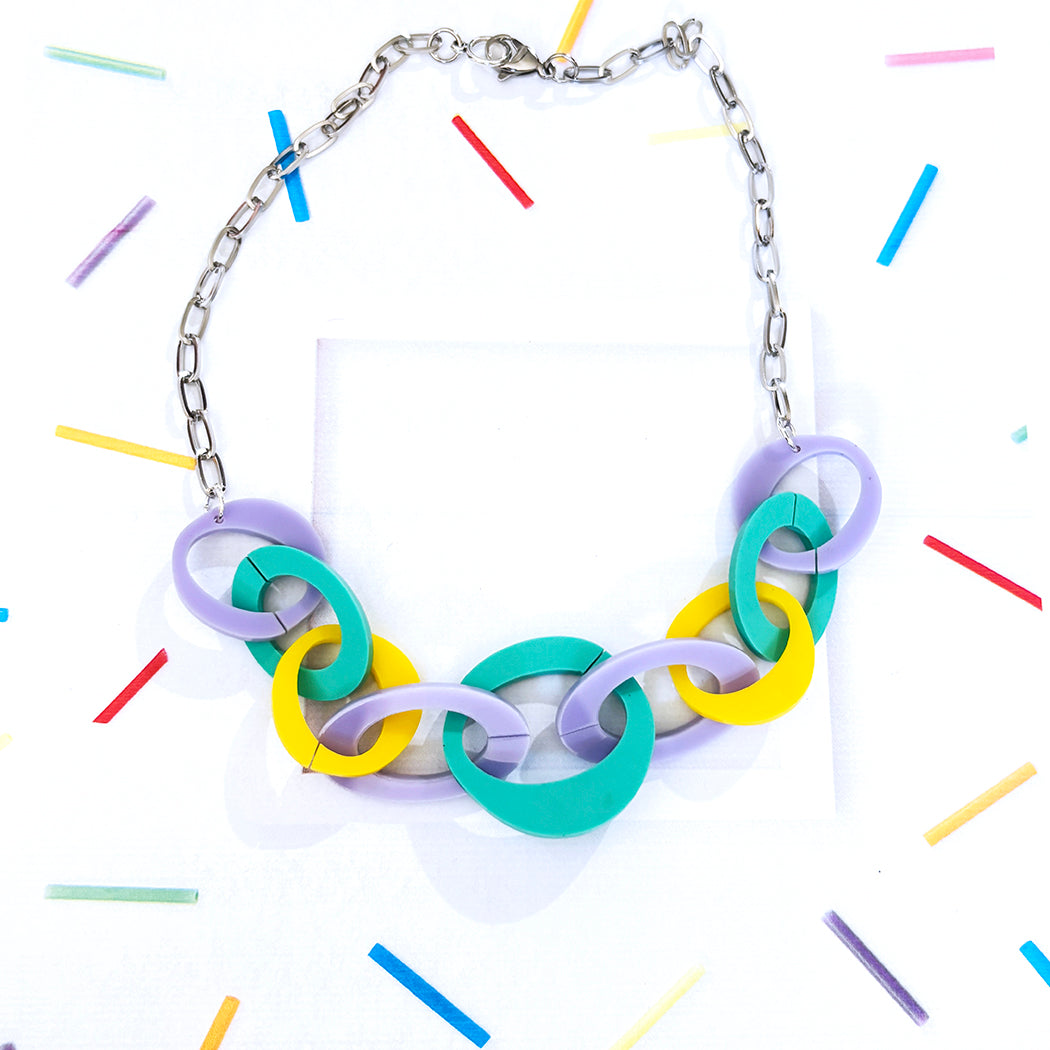 Necklace with colorful chain links on a white background with colorful lines.