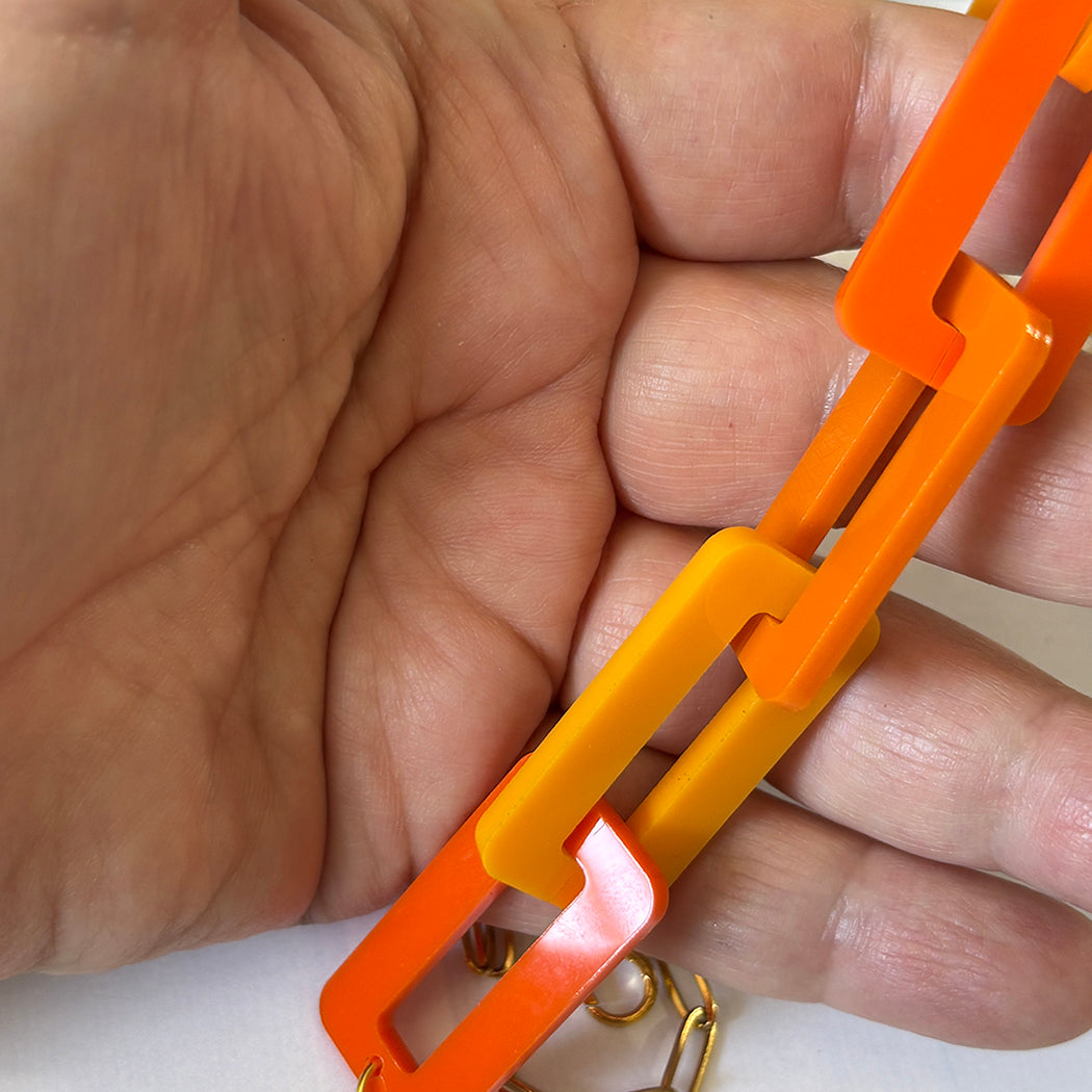 Hand holding an orange and tangerine chain.