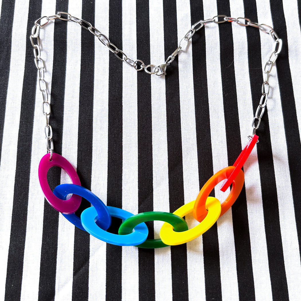 Colorful ROY G BIV chain necklace on a black and white striped background