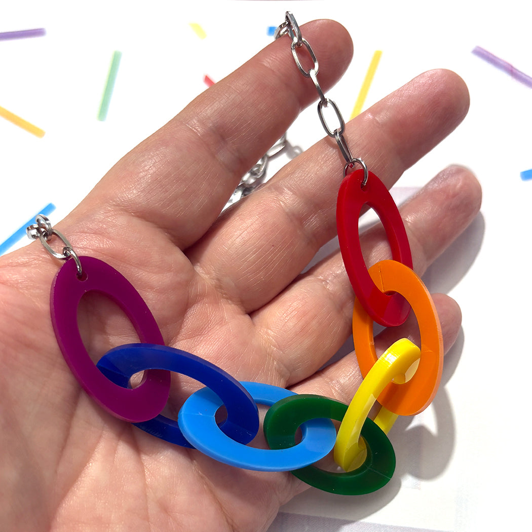 Colorful chain necklace held in a hand with a white background
