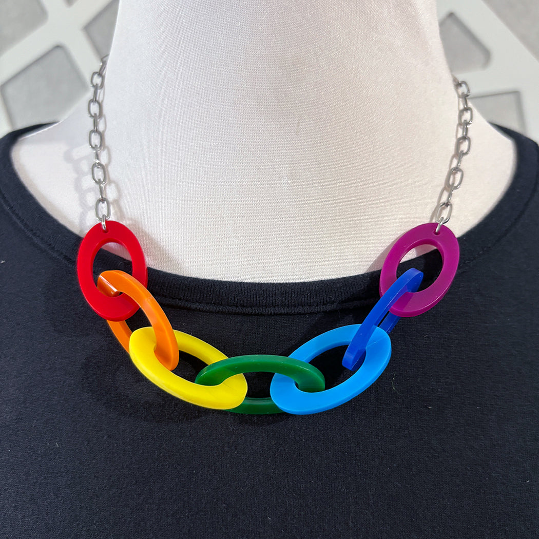 Necklace with rainbow-colored links on a mannequin wearing a black shirt.