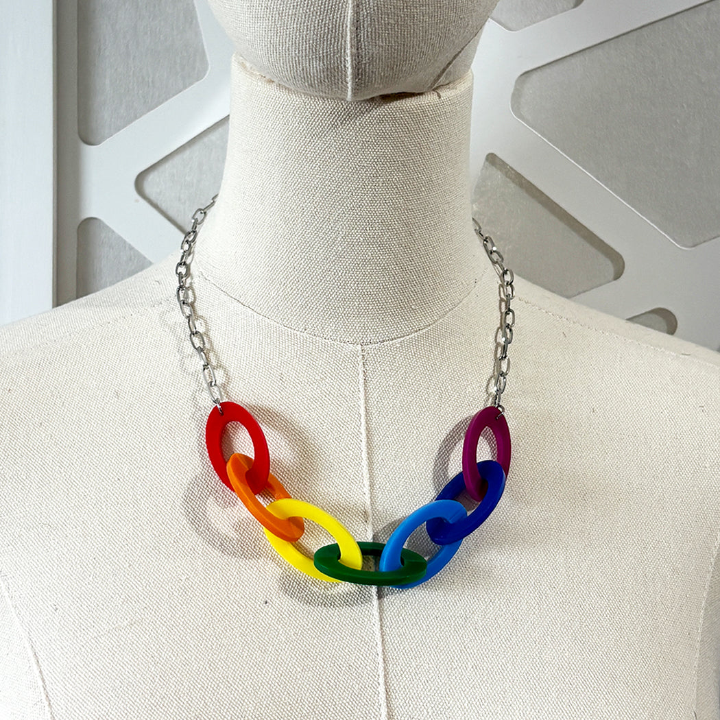 Mannequin wearing a colorful necklace with rainbow links on a neutral background