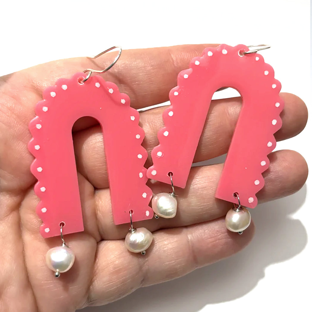 Close up of large pink scalloped arch earrings with freshwater pearl dangles from Audacious Studio. 