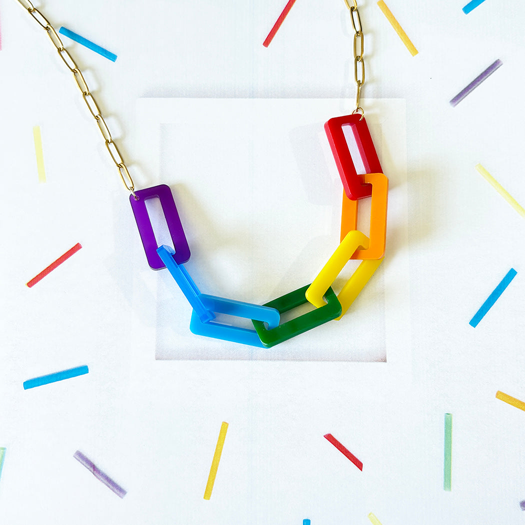 Colorful rainbow necklace with interlocking rings on a white background with colorful lines.