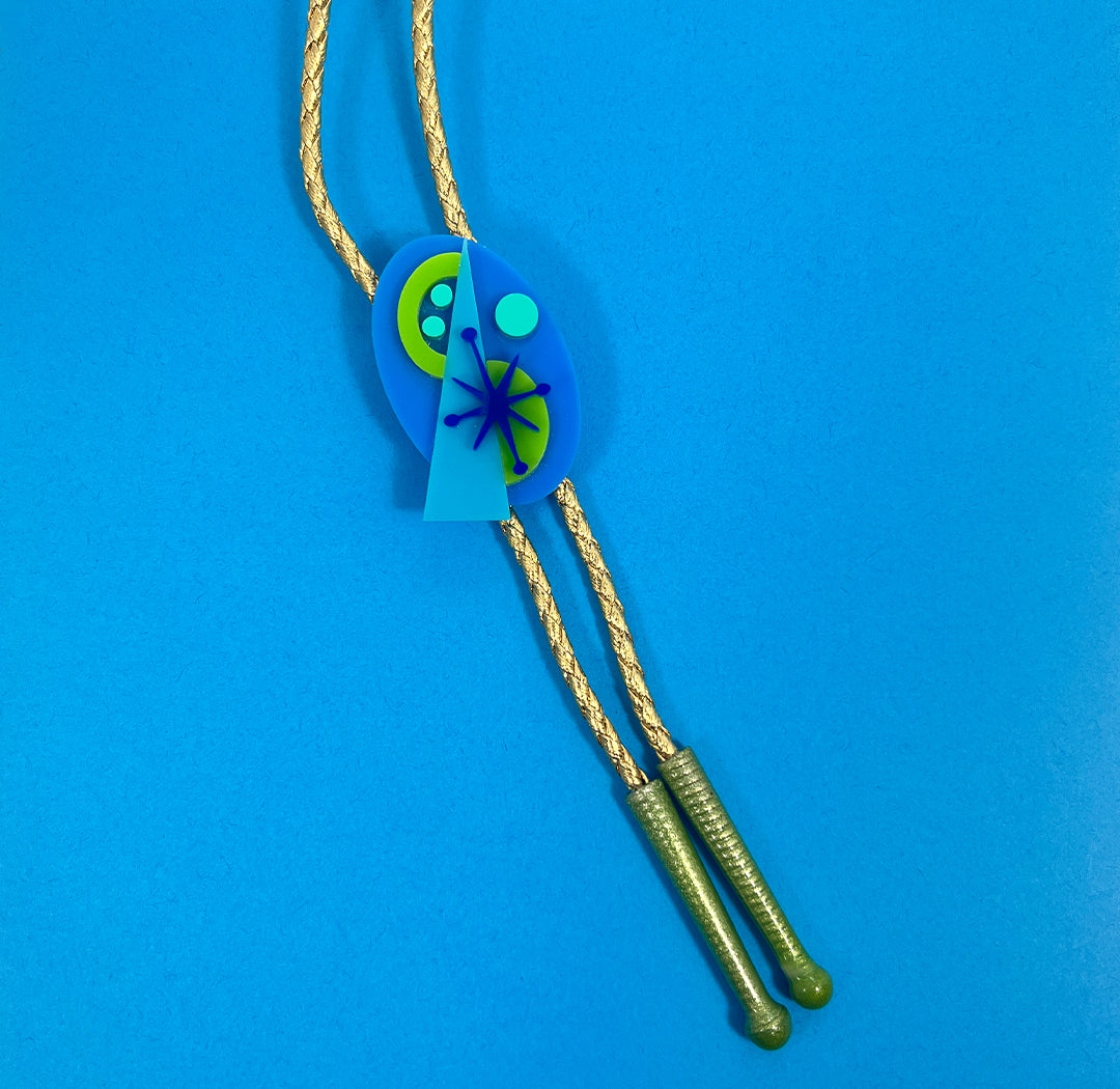 Funky modernist acylic bolo tie in green, aqua and blue. Bolo tie with metallic gold cord and apple green tips from by Barbe jewelry.
