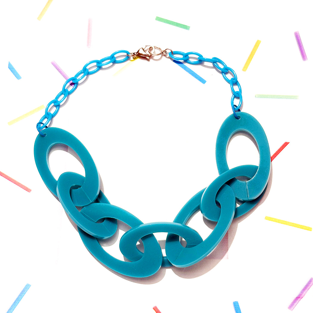 Turquoise teal acrylic chain necklace on a white background with colorful confetti