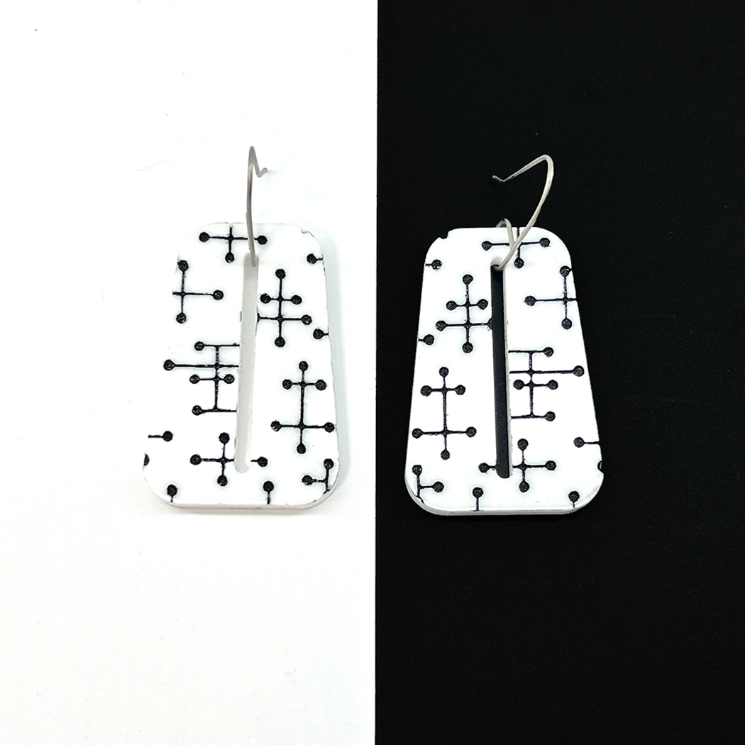 Eames inspired Pin Dot white acylic earrings and black and white background.
